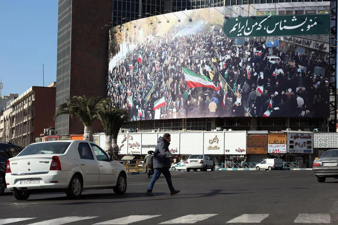 An Iranian walk next to a billboard reading at the Valiasr square in a street in Tehran on Jan 16.