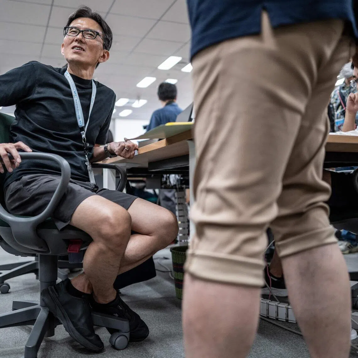 Government officials in casual dress code, including shorts, tee shirts and sneakers, work in the office of the Tokyo Metropolitan Government building.