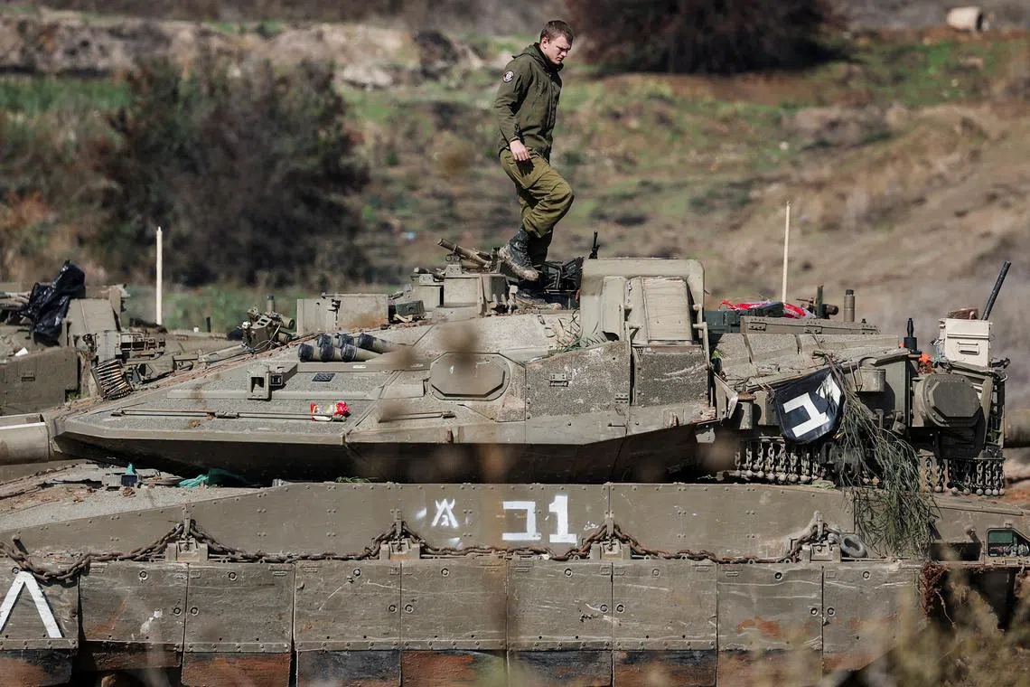 An Israeli soldier stands on a tank near a road leading to the Israel-Lebanon border.