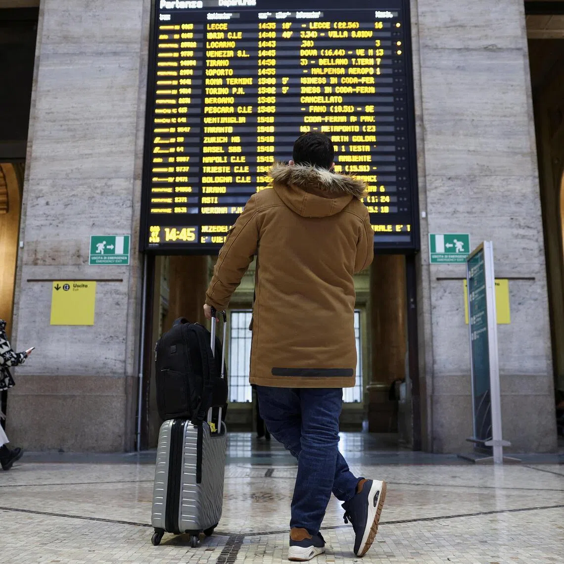 A man looking at a board announcing delays at Milan's train station on Feb 7, as Italian police investigate possible sabotage to electricity cables near the city of Bologna.