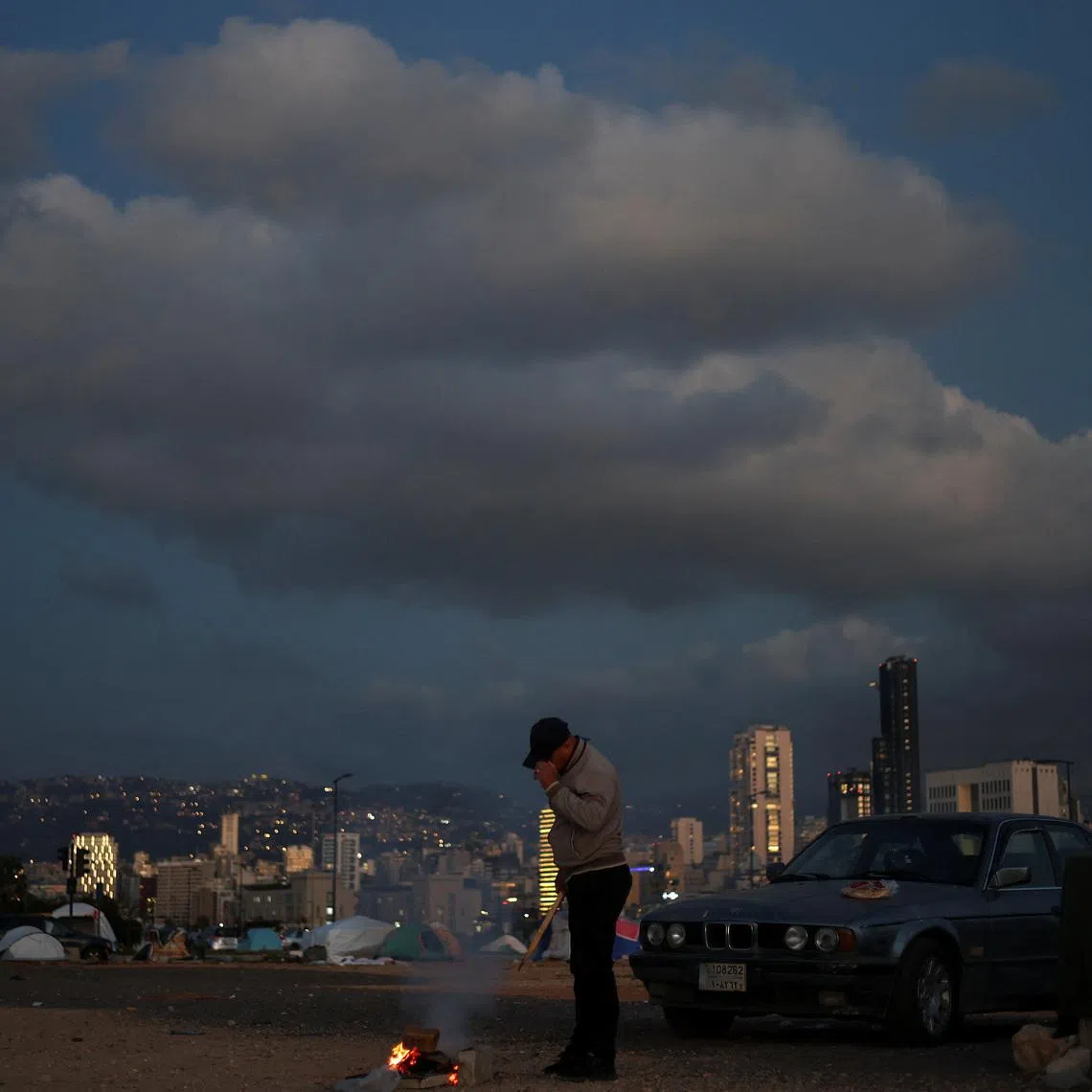 FILE PHOTO: A displaced man lights a fire outside his tent at a makeshift encampment, amid a 10-day ceasefire between Lebanon and Israel, in Beirut, Lebanon, April 21, 2026. REUTERS/Saleh Salem/File Photo