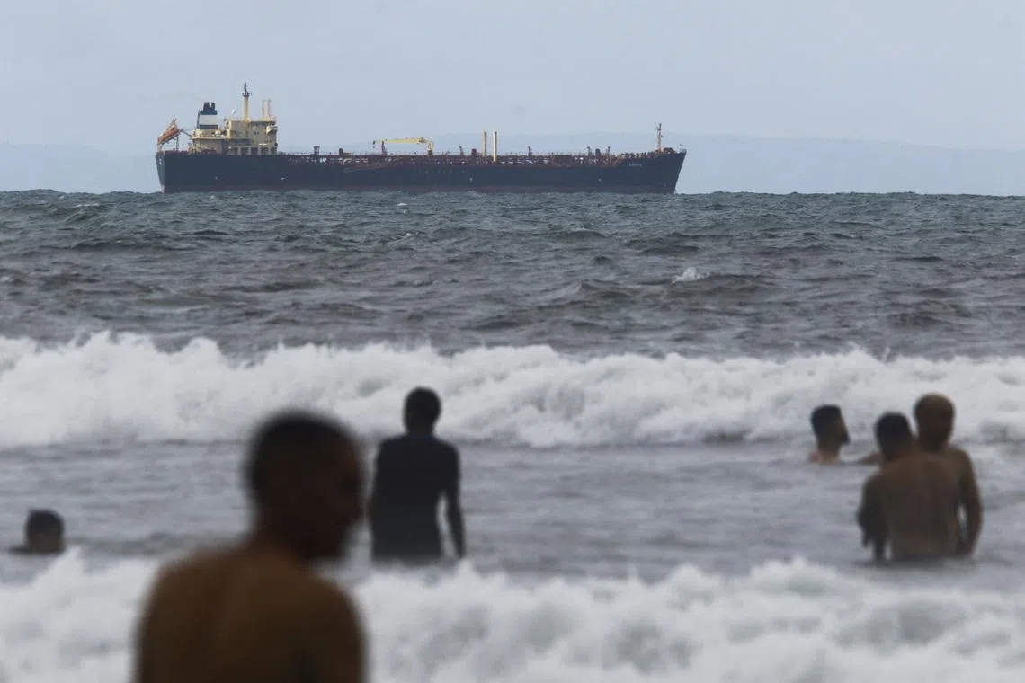 People enjoy the ocean near the Comoros-flagged oil tanker Evana, used to move oil between domestic ports in Venezuela, near El Palito terminal, in Puerto Cabello, Venezuela December 29, 2025. REUTERS/Juan Carlos Hernandez