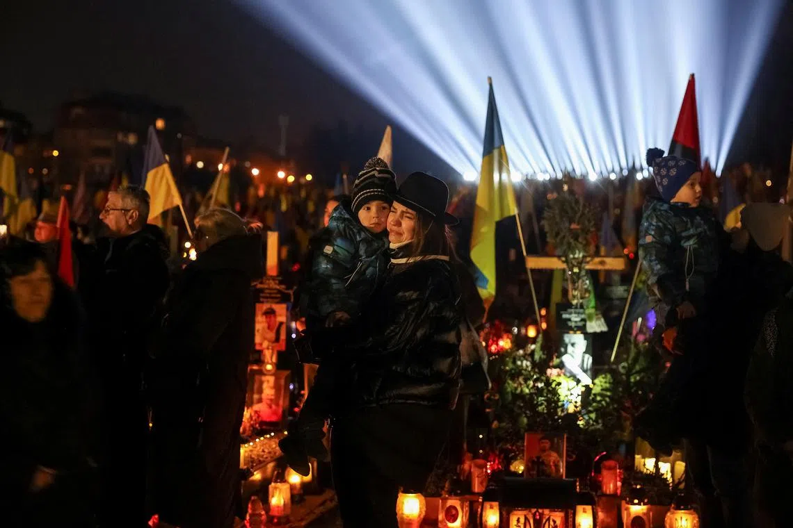 People visit the graves of their relatives, who were killed during Russia's attack on Ukraine, during a large-scale light installation \"Lights of Memory\" as they mark the third anniversary of the full-scale Russian invasion, at the Lychakiv cemetery in Lviv, Ukraine  February 23, 2025. REUTERS/Roman Baluk