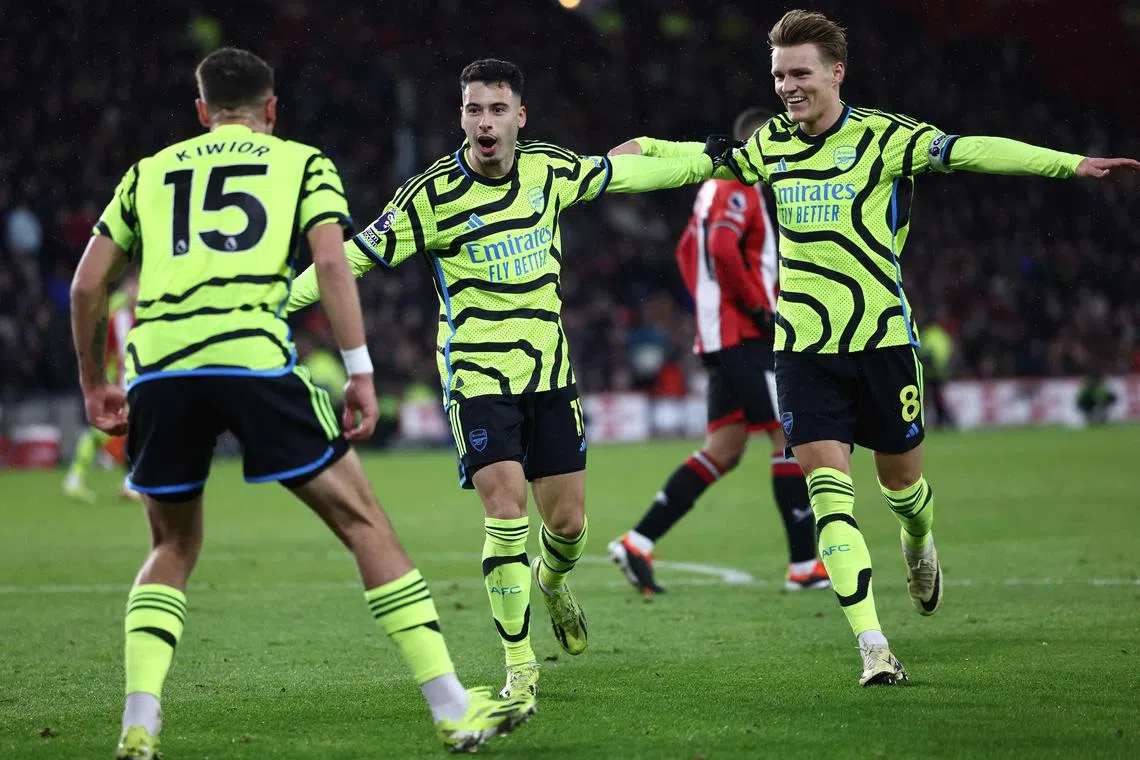 Arsenal's Gabriel Martinelli (centre) celebrating with Jakub Kiwior (No. 15) and Martin Odegaard after scoring the team's third goal against Sheffield United.