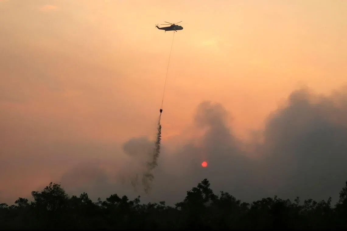 A helicopter dropping water on burning forests in Indonesia’s Central Kalimantan province on Aug 13.