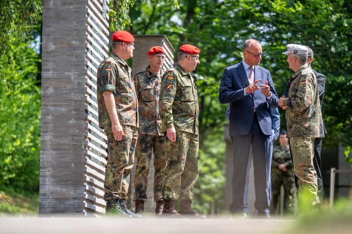 FILE PHOTO: German Chancellor Friedrich Merz talks to soldiers in the so-called \"Forest of Remembrance\" following his visit to the Operational Command of the German armed forces Bundeswehr in Schwielowsee near Berlin, Germany, June 28, 2025.     Michael Kappeler/Pool via REUTERS/File Photo