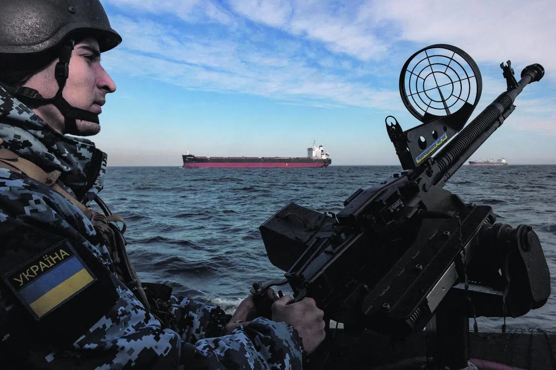 A Ukrainian serviceman manning a gun on a patrol boat as a cargo ship passes by in the Black Sea, amid Russia’s invasion of Ukraine, in February 2024.