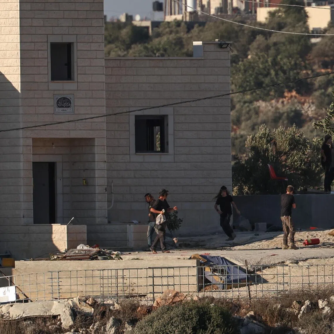 Israeli settlers stand near seized properties belonging to the Palestinian Al-Tubasi family in the West Bank village of Jalud on Aug 25.