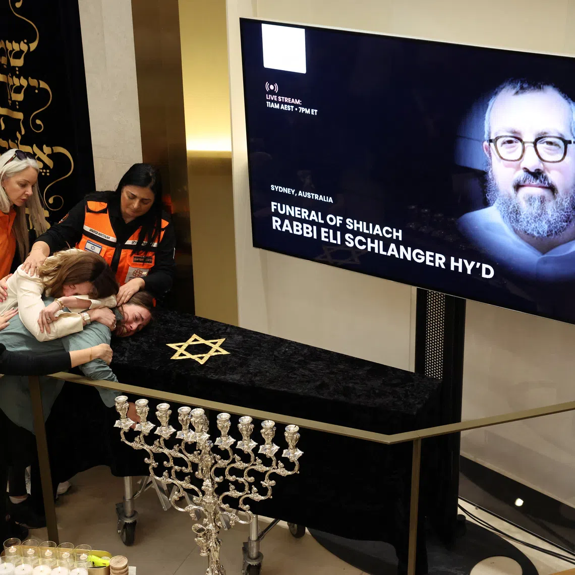 Family members of Rabbi Eli Schlanger, who was killed during a shooting at a Jewish Hanukkah celebration at Sydney's Bondi Beach on Sunday, react as they lean over his casket during a funeral at Chabad of Bondi, in Sydney, Australia, December 17, 2025. REUTERS/Hollie Adams/Pool