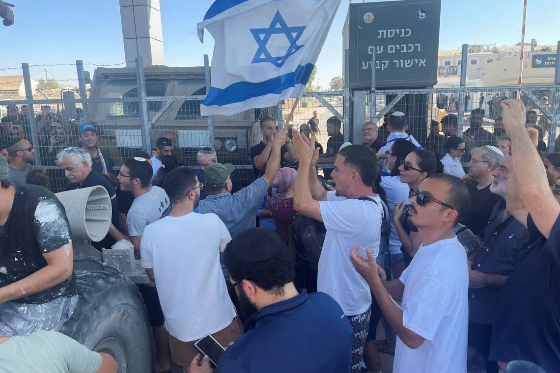 Right-wing protesters wave Israeli flags outside Sde Teiman detention facility, after Israeli Military Police arrived at the site as part of an investigation into suspected abuse of a Palestinian detainee, near Beersheba in southern Israel, July 29, 2024. REUTERS/Jill Gralow