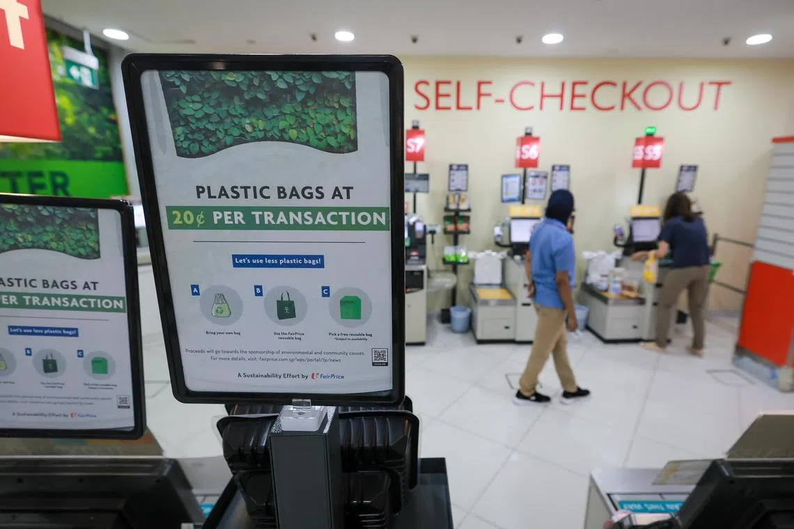 Customers packing their groceries into plastic bags and reusable bags at FairPrice Xtra at Kallang Wave Mall, March 30, 2023.