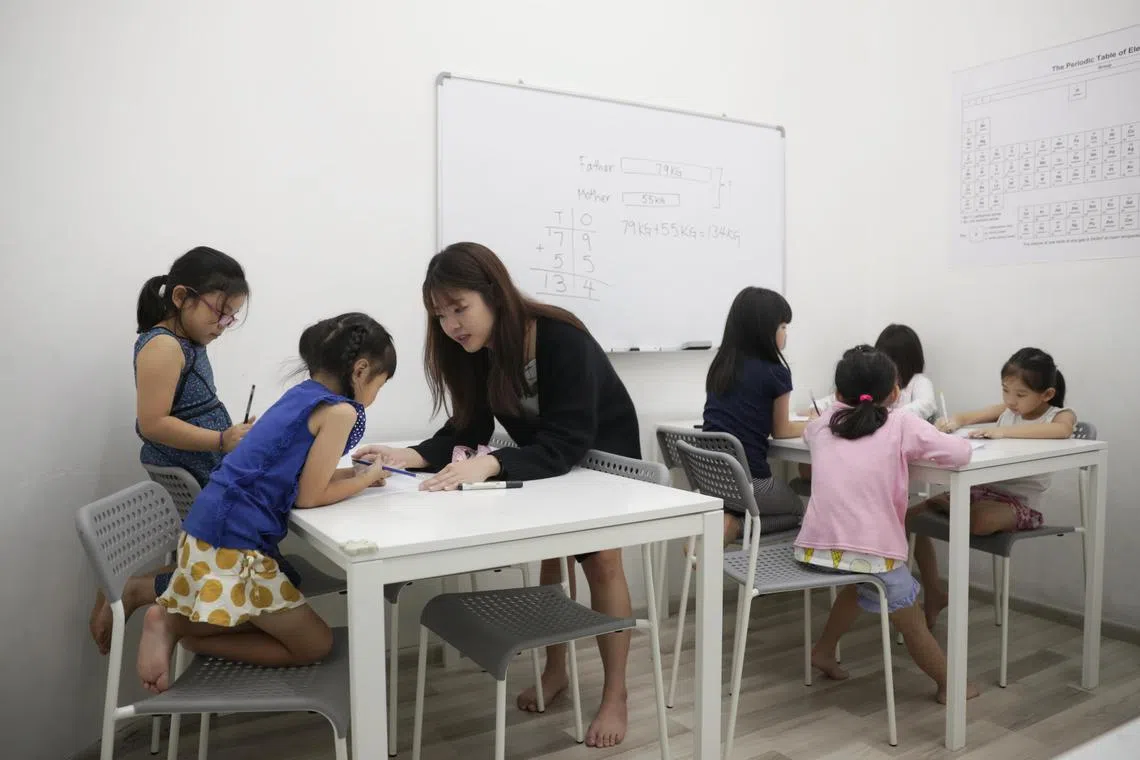 Full-time tutor Calister Ng Jing Ni tutoring Tan Xin Jie Kaelyn (left) and Isabella Chew Xin Yi (second from left), at EduFirst Learning Centre on 5 December 2019.