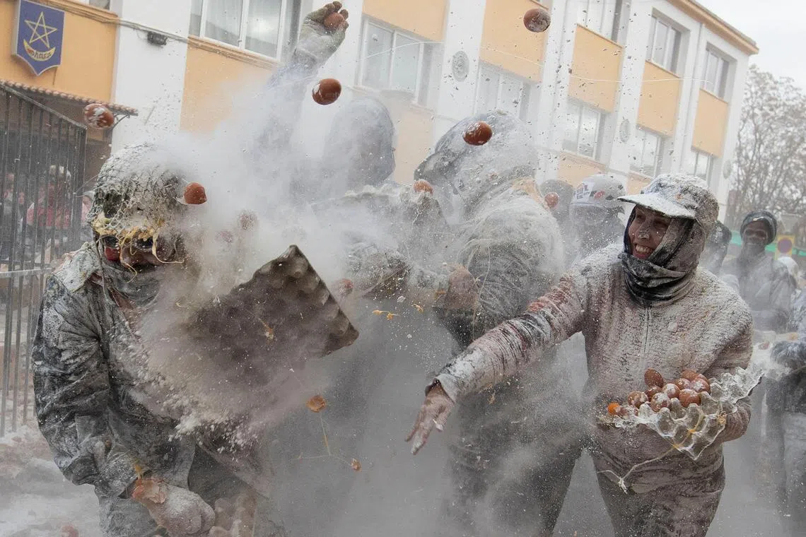 Revellers dressed in mock military garb take part in "Els Enfarinats" flour-battle in the southeastern Spanish town of Ibi on December 28, 2024. In this 200-year-old traditional winter festival, the participants --known as Els Enfarinats (those covered in flour)-- dress in military clothes and stage a mock coup d'etat as they battle using flour, eggs and firecrackers outside the town hall as part of the celebrations of the Day of the Innocents, a traditional day in Spain for pulling pranks. (Photo by JAIME REINA / AFP)