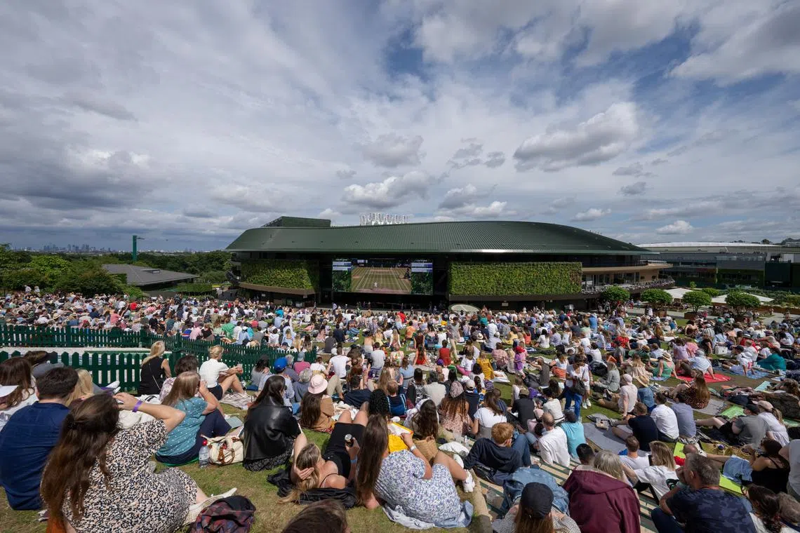 FILE PHOTO: Tennis - Wimbledon - All England Lawn Tennis and Croquet Club, London, Britain - July 11, 2021   Spectators watch the men's final on a large screen as they sit on Henman Hill Pool via REUTERS/Andrew Baker/File Photo