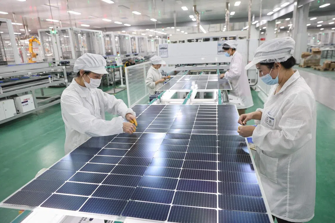 (FILES) This file photo taken on January 4, 2024 shows employees working on solar photovoltaic modules that will be exported at a factory in Lianyungang, in China's eastern Jiangsu province. China is building almost twice as much wind and solar energy capacity as every other country combined, research published on July 11, 2024 showed. (Photo by AFP) / China OUT