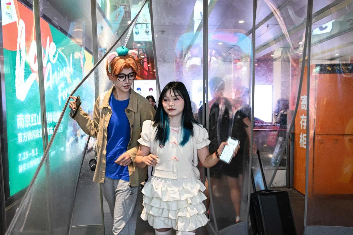 Cosplayer Xu Yunting (left), dressed as Jesse, a male character from the video game 'Light and Night', and Ms Feng Xinyu (right) walked through a mall. 