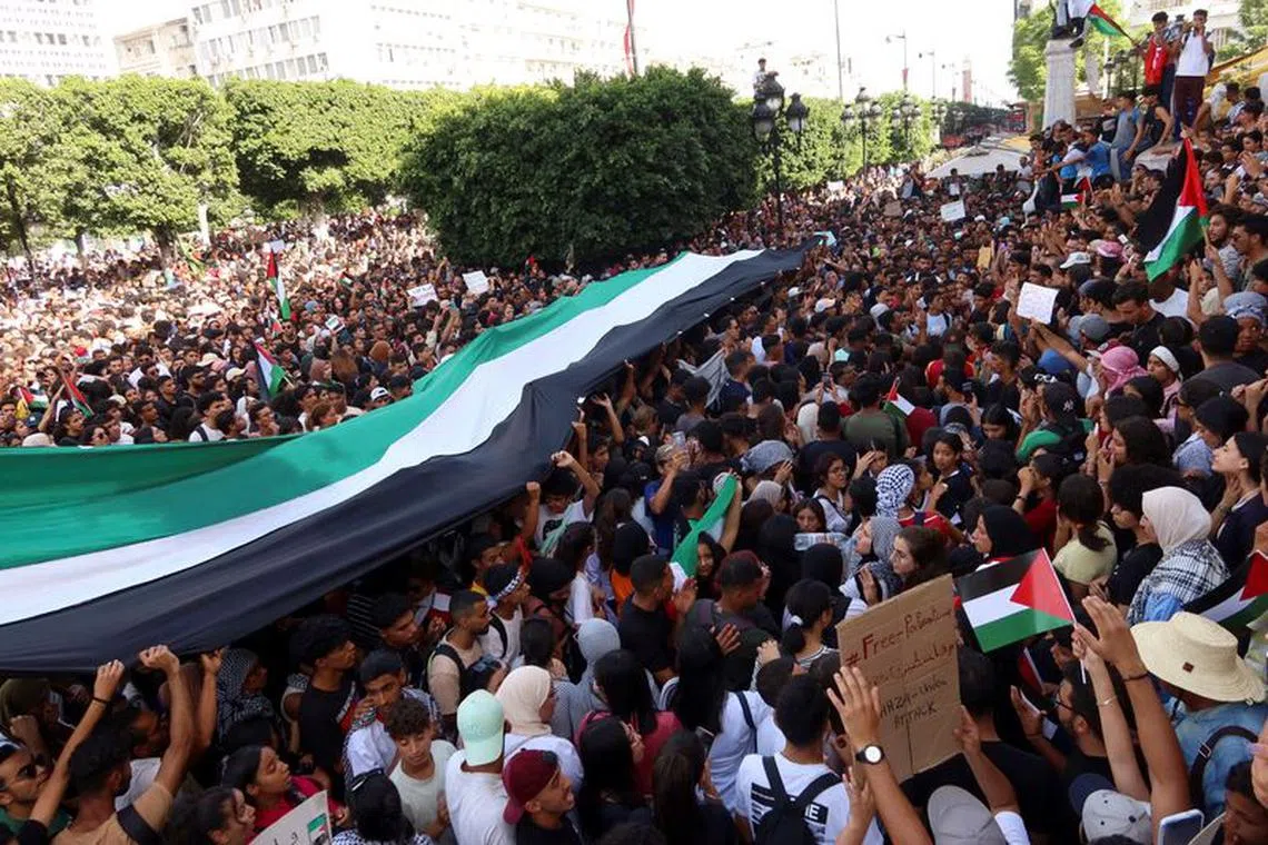People hold flags and during a pro-Palestinian protest after hundreds of Palestinians were killed in a blast at Al-Ahli hospital in Gaza that Israeli and Palestinian officials blamed on each other, in Tunis, Tunisia October 18, 2023. REUTERS/Jihed Abidellaoui