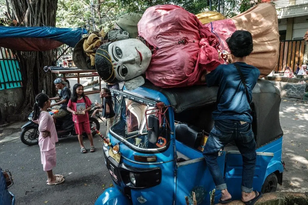 A pair of ondel-ondel puppets are being carried on the roof of a motor tricycle heading to a performance in Jakarta on May 4, 2025. Ondel-ondel are giant traditional puppets from Jakarta's Betawi culture, originally used in rituals and festive parades to ward off evil spirits. 