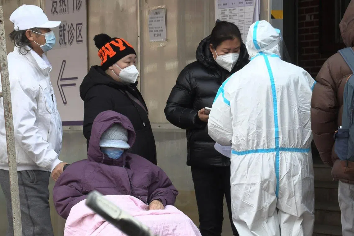 This frame grab from AFPTV video footage shows a woman talking with a health worker as people queue outside a fever clinic amid the Covid-19 pandemic in Beijing on December 14, 2022. (Photo by Yuxuan ZHANG / various sources / AFP)
