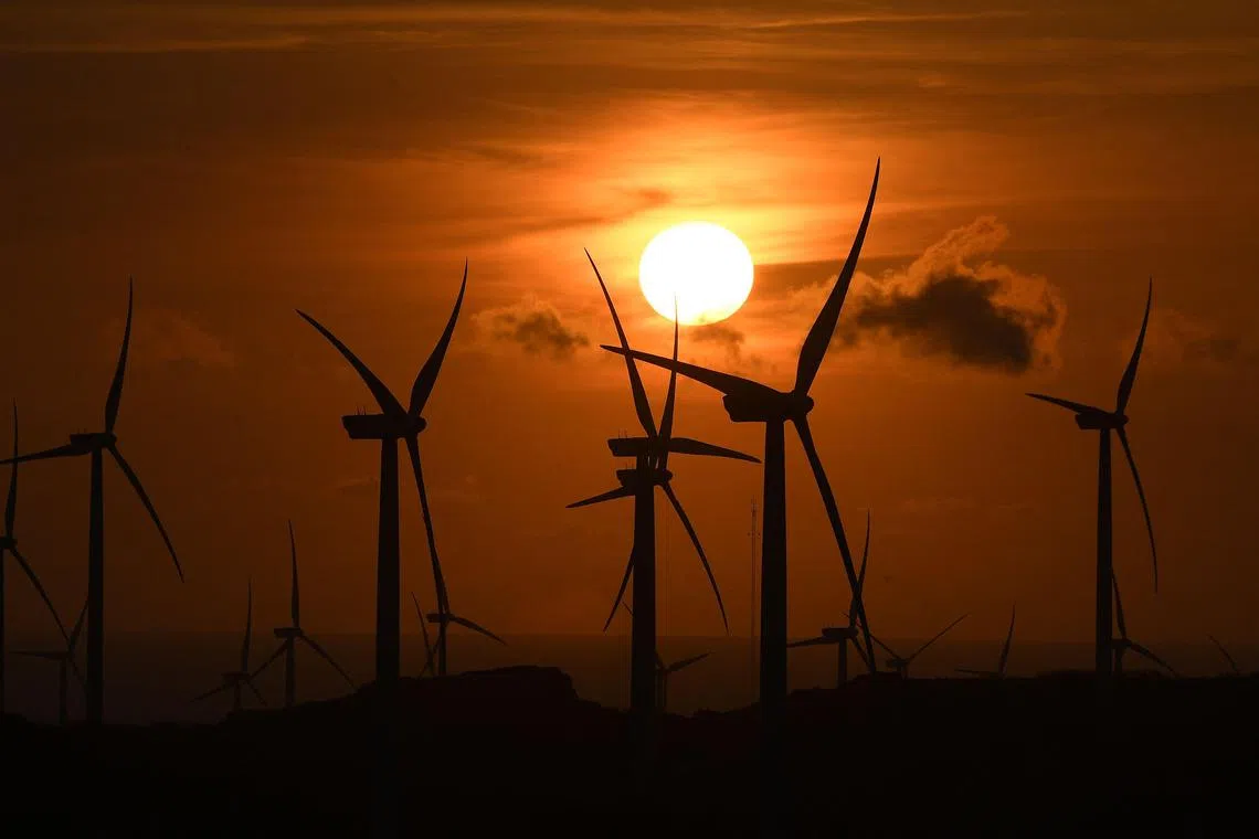 The sun sets next windmills in Burgos town, in Ilocos norte province on May 8, 2024. (Photo by Ted ALJIBE / AFP)
