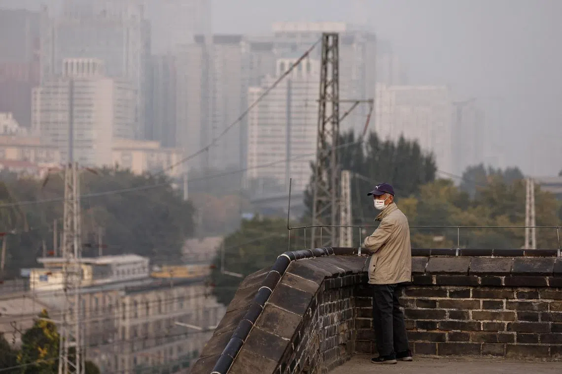 A person wearing a face mask stands at the Ming Dynasty City Wall Relics Park, as Beijing issues orange alert for heavy air pollution, in Beijing, China October 31, 2023. REUTERS/Tingshu Wang