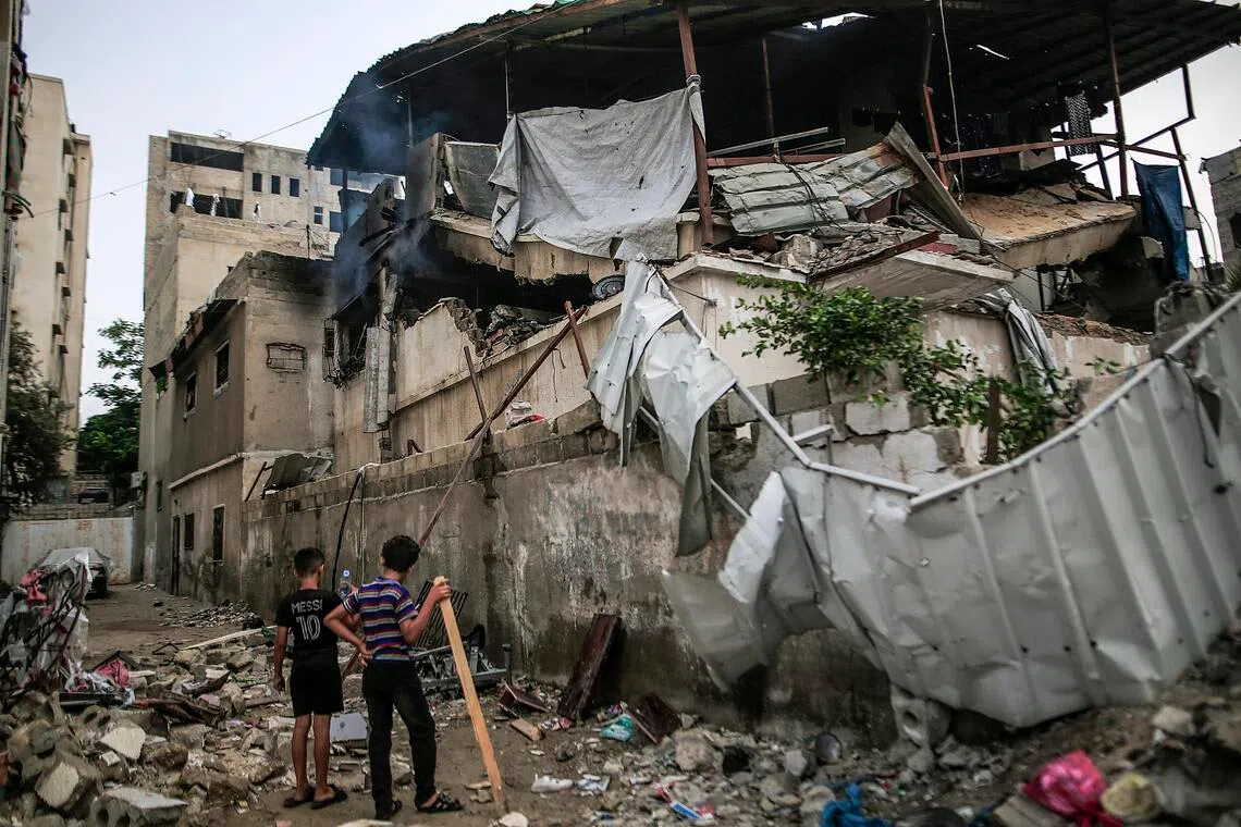 Palestinian youths stand amid the rubble from the destroyed house of the Al-Masri family following an Israeli attack, in Gaza City.