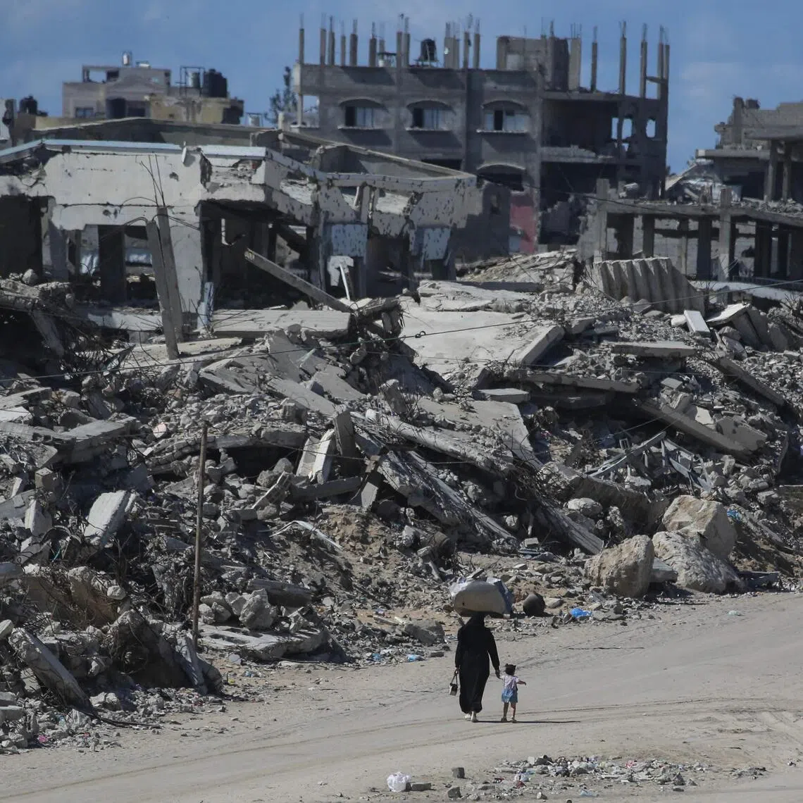 Palestinians walking along destroyed buildings at the Jabalia refugee camp in the Gaza Strip on Oct 5. Israel’s years-long military campaign in Gaza has killed more than 74,200 people, according to the Palestinian Health Ministry.