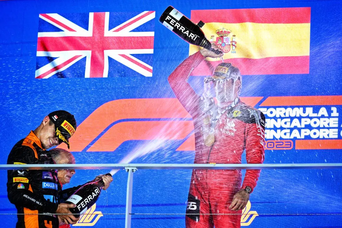 Lando Norris of McLaren Formula 1 Team  spraying champagne onto Carlos Sainz of Scuderia Ferrari celebrating his win during the trophy presentation at the Formula One Singapore Airlines Singapore Grand Prix on Sept 17.