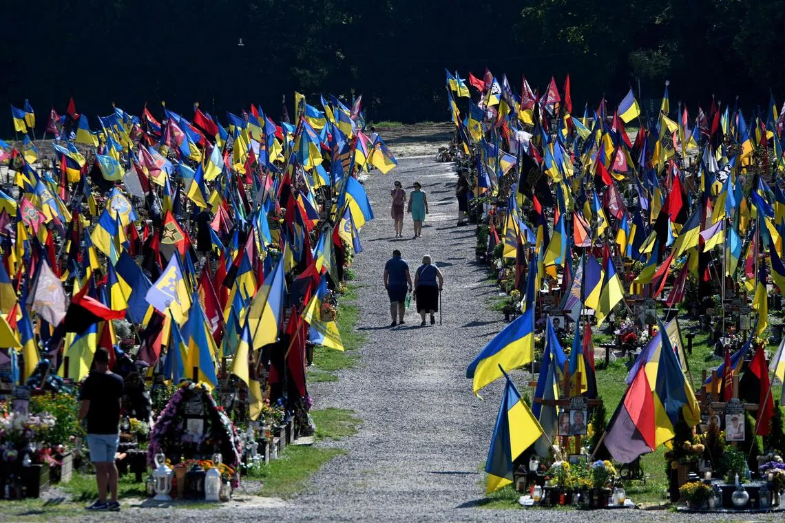 People walking through the cemetery of Lychakiv as they pay tribute to fallen soldiers in the struggle for independence, sovereignty and territorial integrity of Ukraine during the Day of Remembrance of the Defenders of Ukraine, in Lviv on August 29, 2023, amid the Russian invasion of Ukraine. 