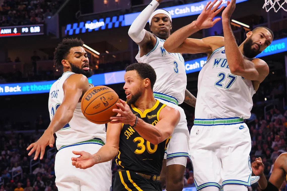 Golden State Warriors guard Stephen Curry (30) passing the ball out between Minnesota Timberwolves center Karl-Anthony Towns (32), forward Jaden McDaniels (3), and center Rudy Gobert (27) during the fourth quarter at Chase Center. 
