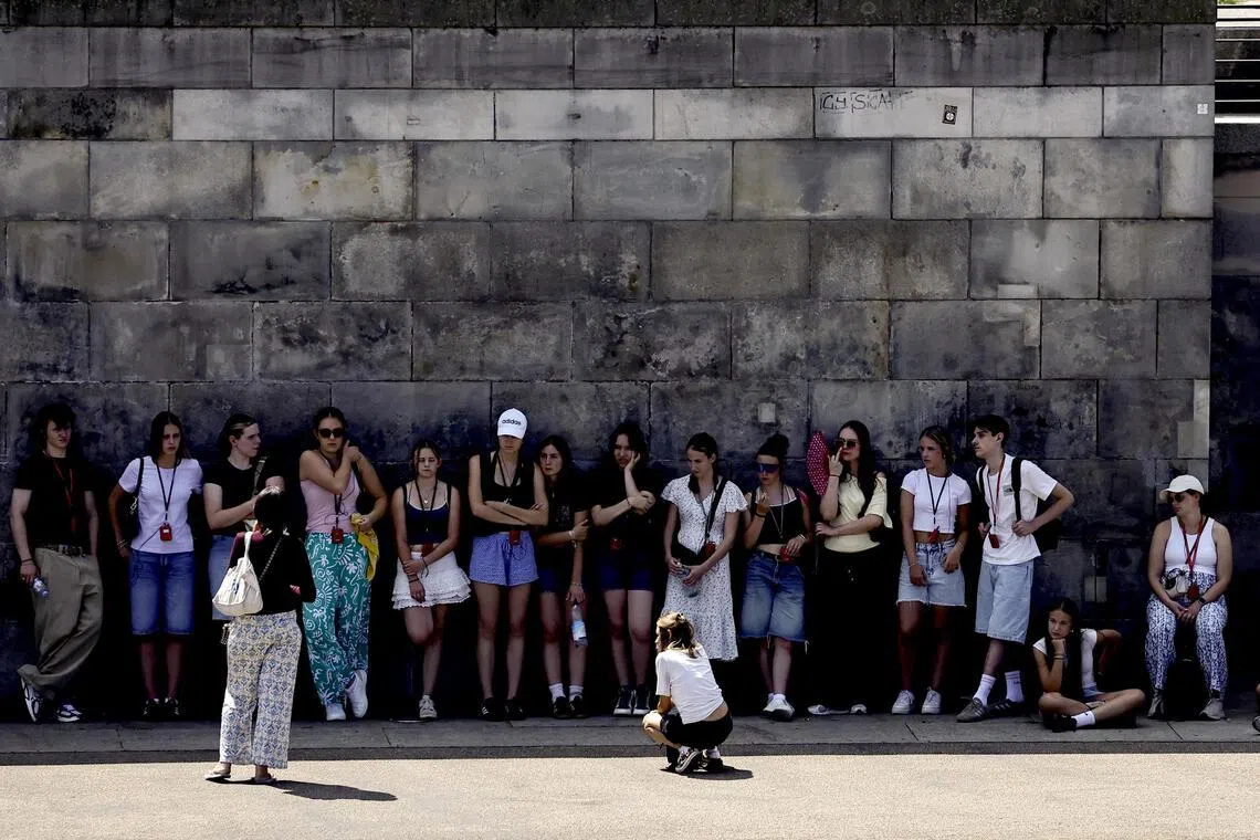 Tourists rest in the shade along the banks of the Spree River on a summer day in Berlin.