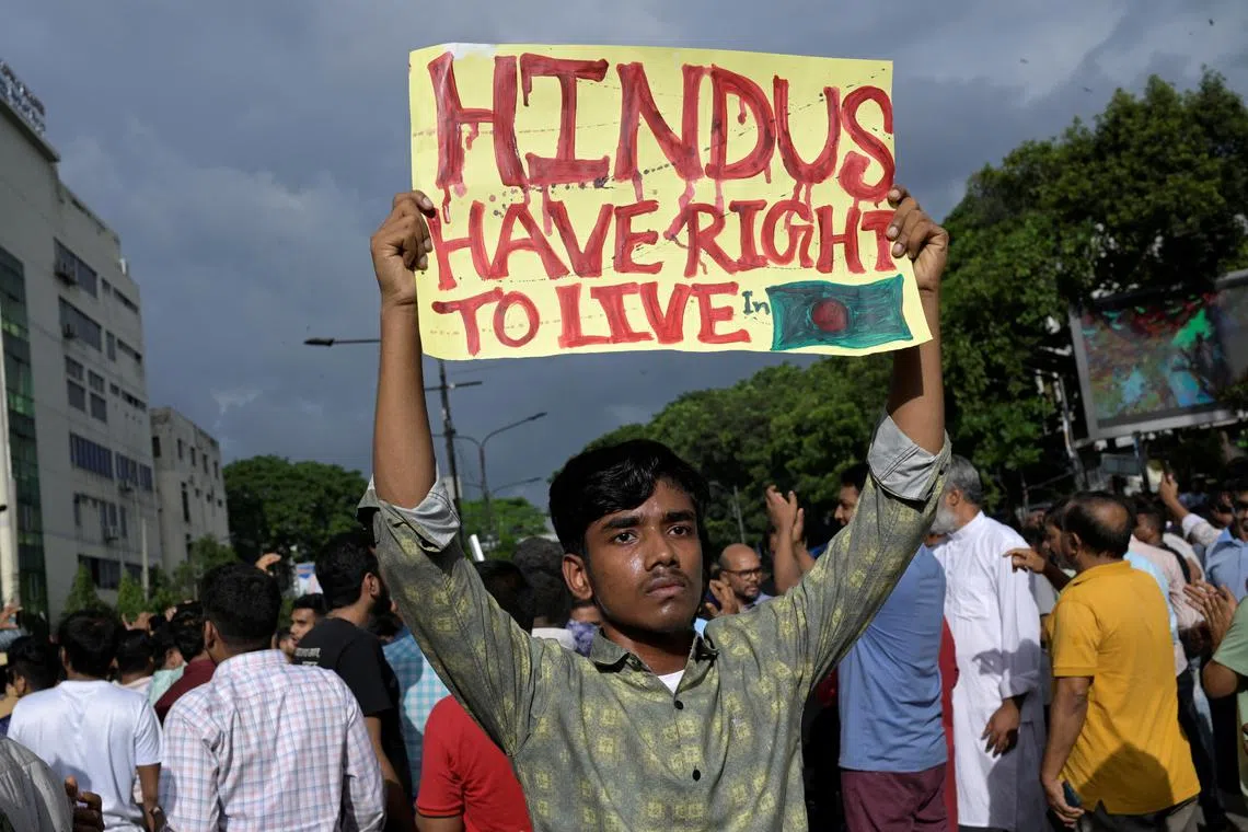 A demonstrator in Dhaka on Aug 9 displays a placard during a protest of violence against Hindu communities during ongoing unrest.