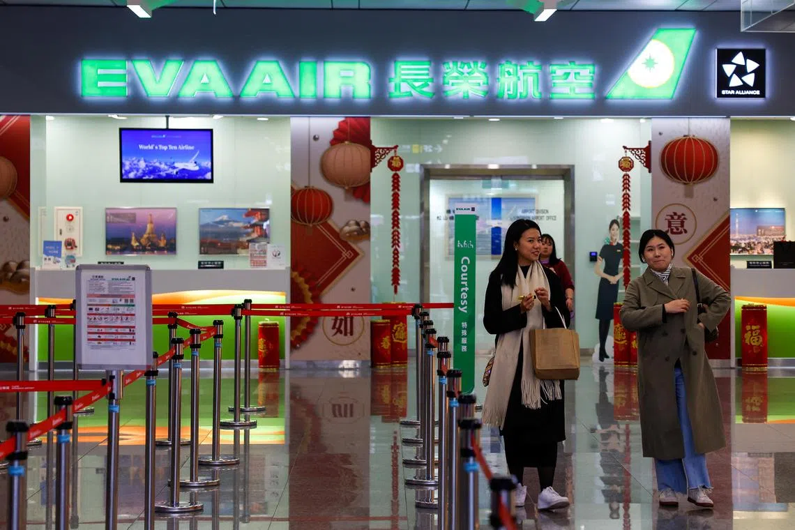 People walk in front of an Eva Air office at Songshan Airport Taipei, Taiwan.