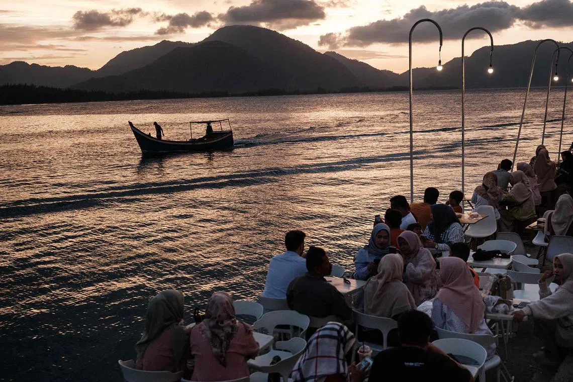 People enjoy an oceanfront cafeteria built on the site where all houses were destroyed by the 2004 Indian Ocean tsunami, in Banda Aceh, on December 25, 2024, on the eve of the tsunami's 20th anniversary. On December 26, 2004, a magnitude 9.1 earthquake struck the coast of Sumatra in Indonesia and triggered a huge tsunami across the Indian Ocean that killed more than 220,000 people in a dozen countries. (Photo by Yasuyoshi CHIBA / AFP)