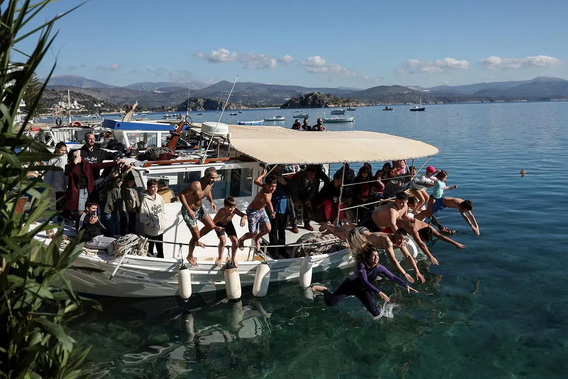 Young believers jump into the sea to catch a wooden cross, during the Epiphany day celebrations in the fishing village of Tolo, Greece, January 6, 2025. REUTERS/Louisa Gouliamaki TPX IMAGES OF THE DAY
