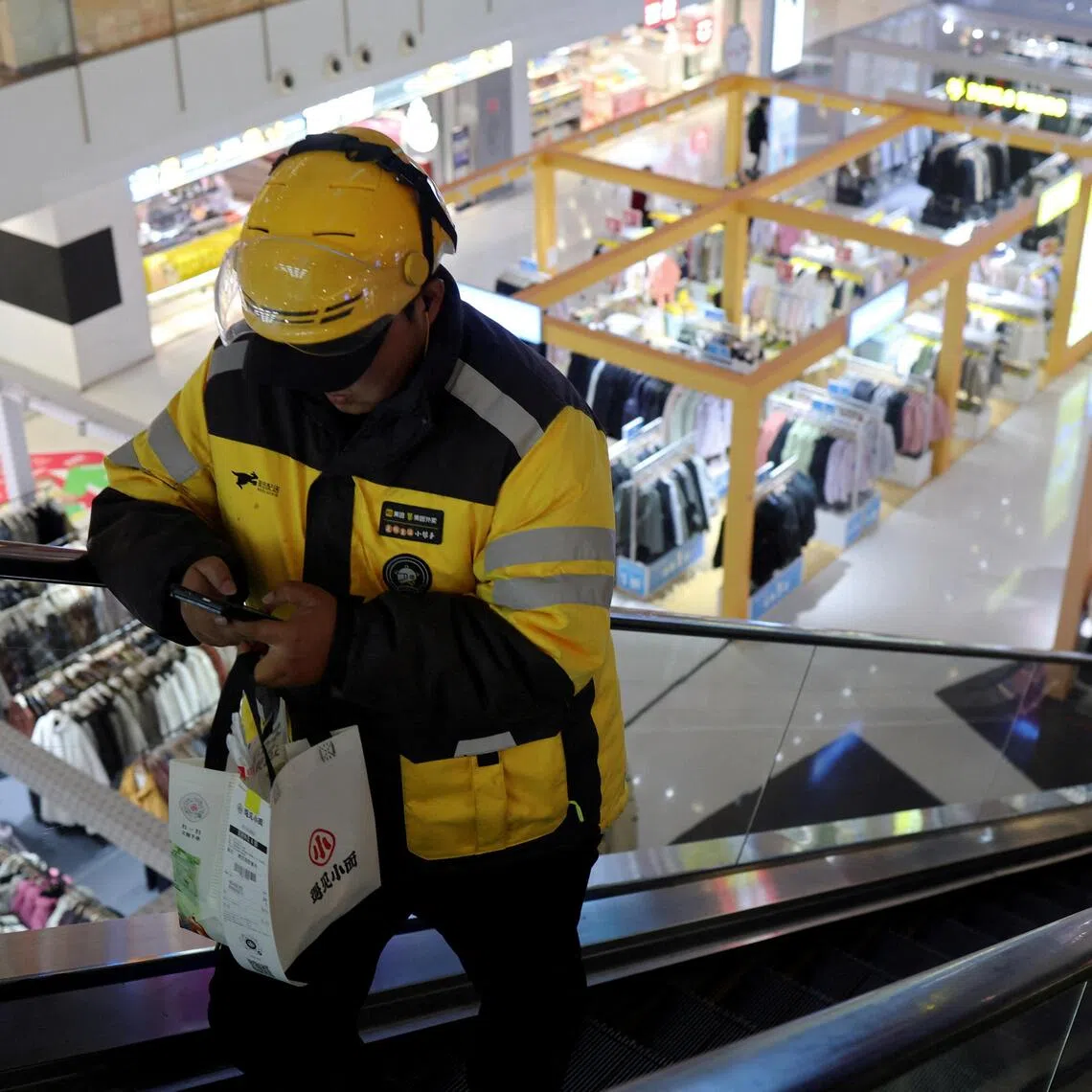 FILE PHOTO: A Meituan delivery worker picks up a food order at a shopping mall in Beijing, China October 17, 2024. REUTERS/Florence Lo/File Photo