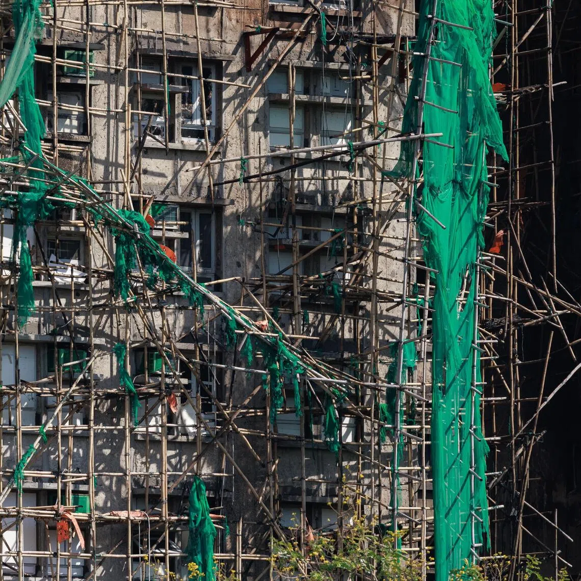 epa12555484 Bamboo scaffolding and construction mesh cling to the burnt-out structure in the aftermath of the Tai Po apartment fire in Hong Kong, China, 28 November 2025. The fire, which started on 26 November, has killed at least 128 people, and left hundreds missing.  EPA/MAY JAMES
