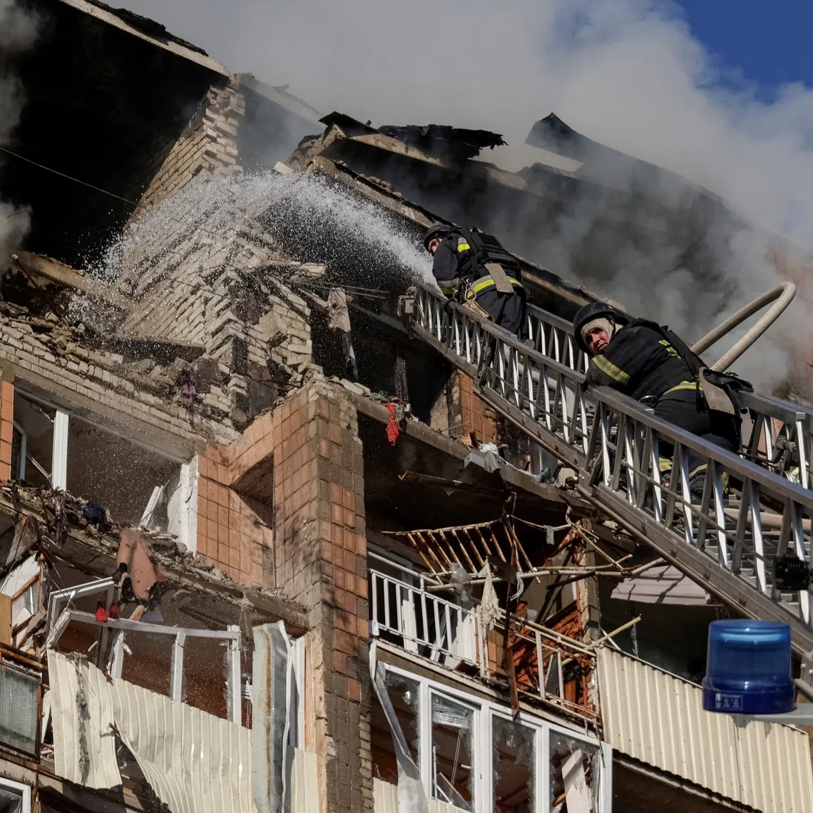 Firefighters work at the site of an apartment building damaged during a Russian drone strike in Kharkiv, Ukraine, on Oct 12.