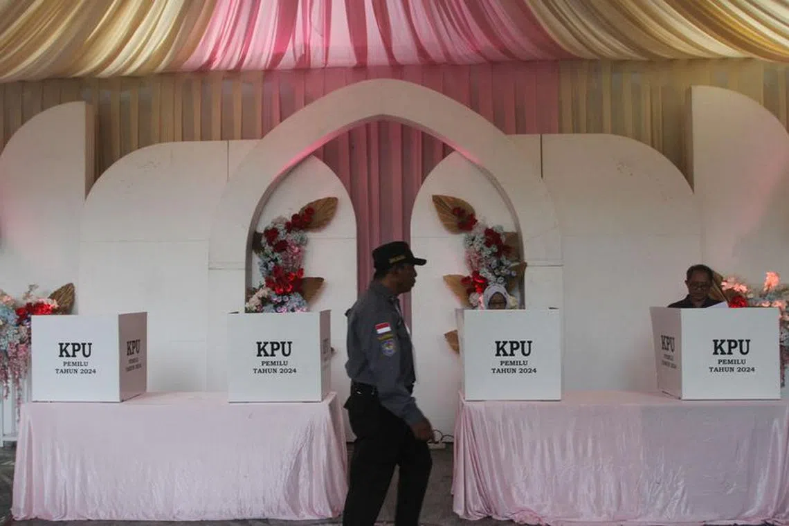 A member of the Linmas civil defence force passes by ballot boxes at a Valentine's Day themed polling station during the general election in Malang, East Java, Indonesia February 14, 2024. Antara Foto/Ari Bowo Sucipto via REUTERS
