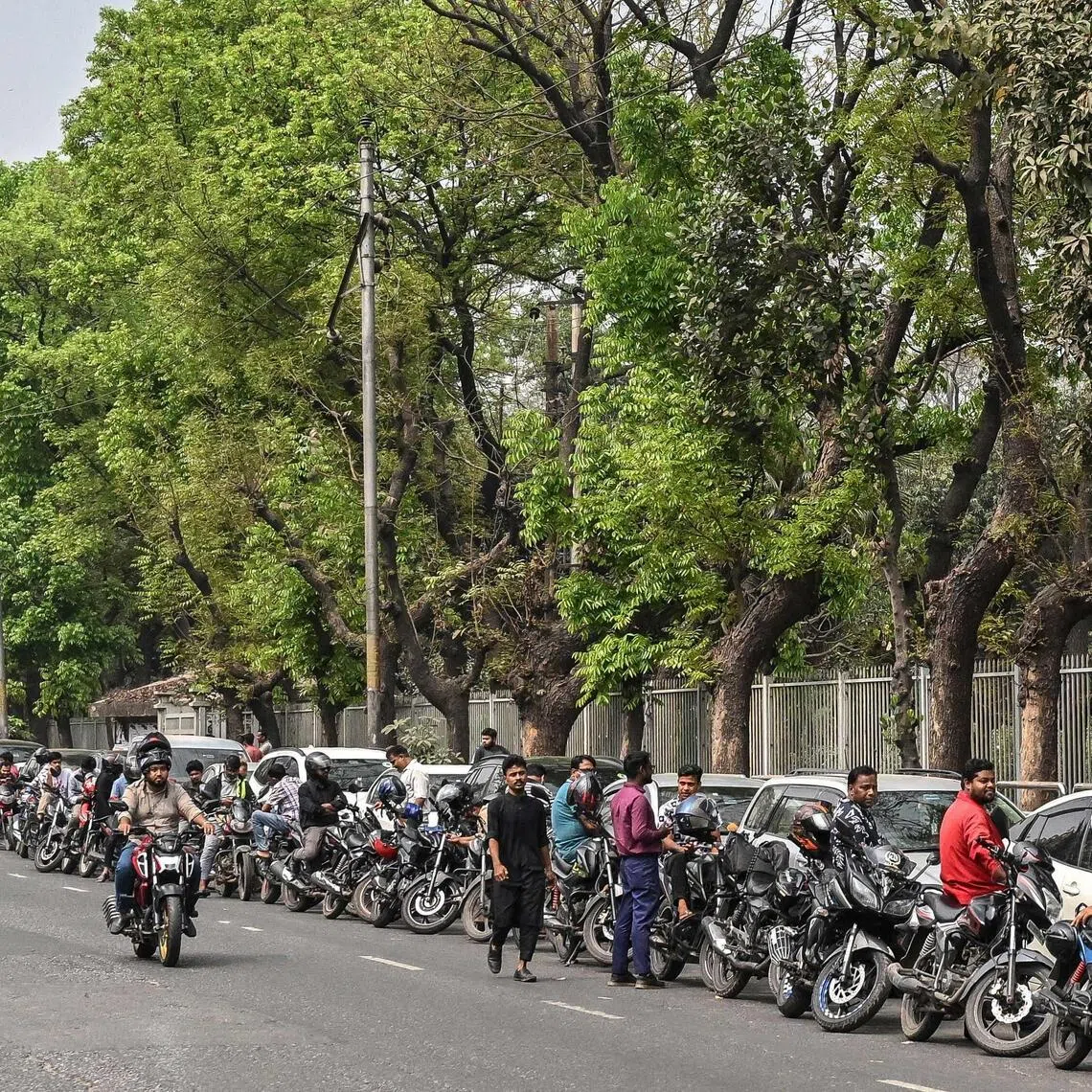 People wait in a queue to refuel their vehicles near a fuel station in Dhaka on March 8, 2026.  