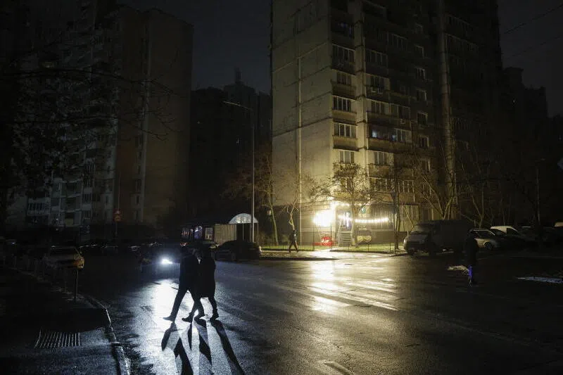 People walk a dark street during an electricity cut-off in Kyiv, Ukraine, on Dec 27, amid the ongoing Russian bombardment.