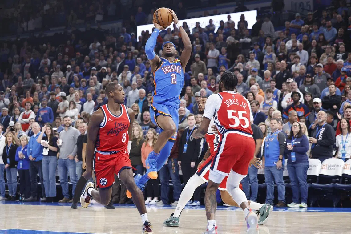 Oklahoma City Thunder guard Shai Gilgeous-Alexander shoots between Los Angeles Clippers guard Kris Dunn and forward Derrick Jones Jr. during the first quarter at Paycom Center.
