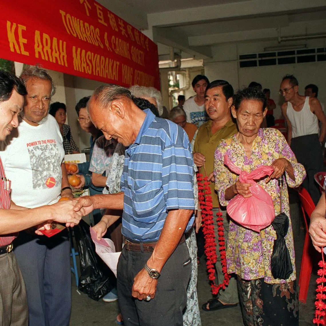 Workers' Party MP Low Thia Khiang (left) and party secretary-general J.B. Jeyaretnam (next to him) distributing hongbao and food hampers to poor, elderly residents in Hougang.