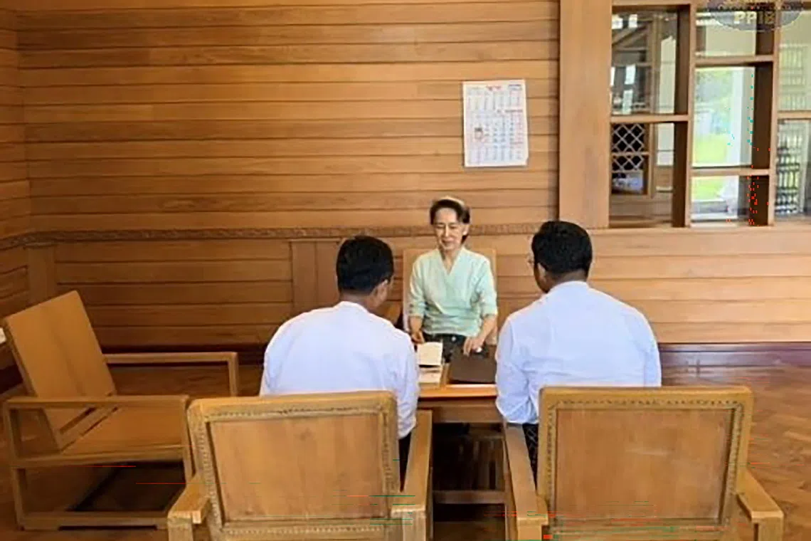 Myanmar’s former leader Aung San Suu Kyi receives books and a letter from Britain’s King Charles from a Myanmar official in Naypyitaw on Oct 19.