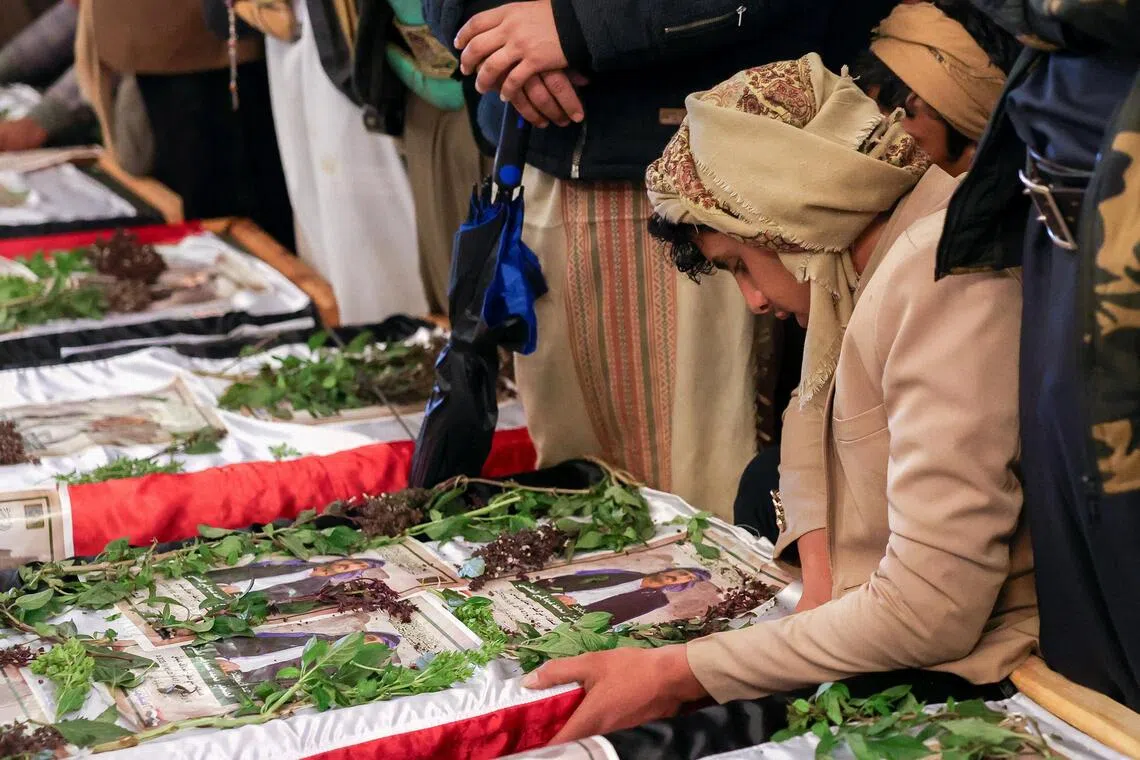 A mourner looks at a picture of a relative displayed on his coffin during the funeral of members of the Houthi military media killed in Israeli airstrikes.