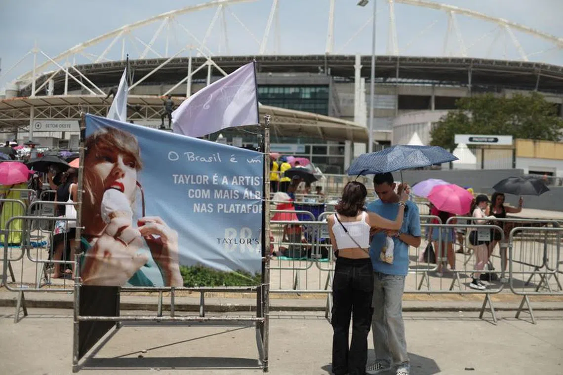 A couple protect themselves with an umbrella for high temperatures, as they wait before the Taylor Swift concert, following the death of a fan due to the heat during the first day concert, in Rio de Janeiro, Brazil, November 18, 2023. REUTERS/Pilar Olivares/File Photo
