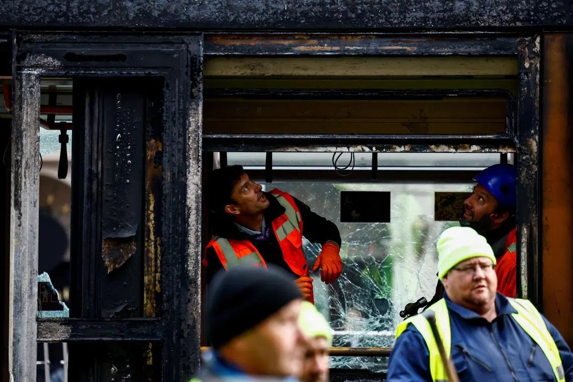 Workers inspect a burned-out tram, following the November 2023 riots in Dublin.