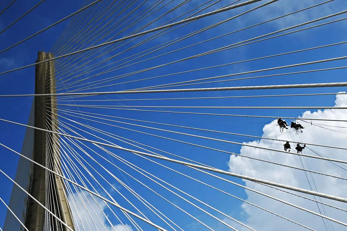 TOPSHOT - Workers conduct maintenance work on the Bandra-Worli Sea Link in Mumbai on September 25, 2023. (Photo by Punit PARANJPE / AFP)