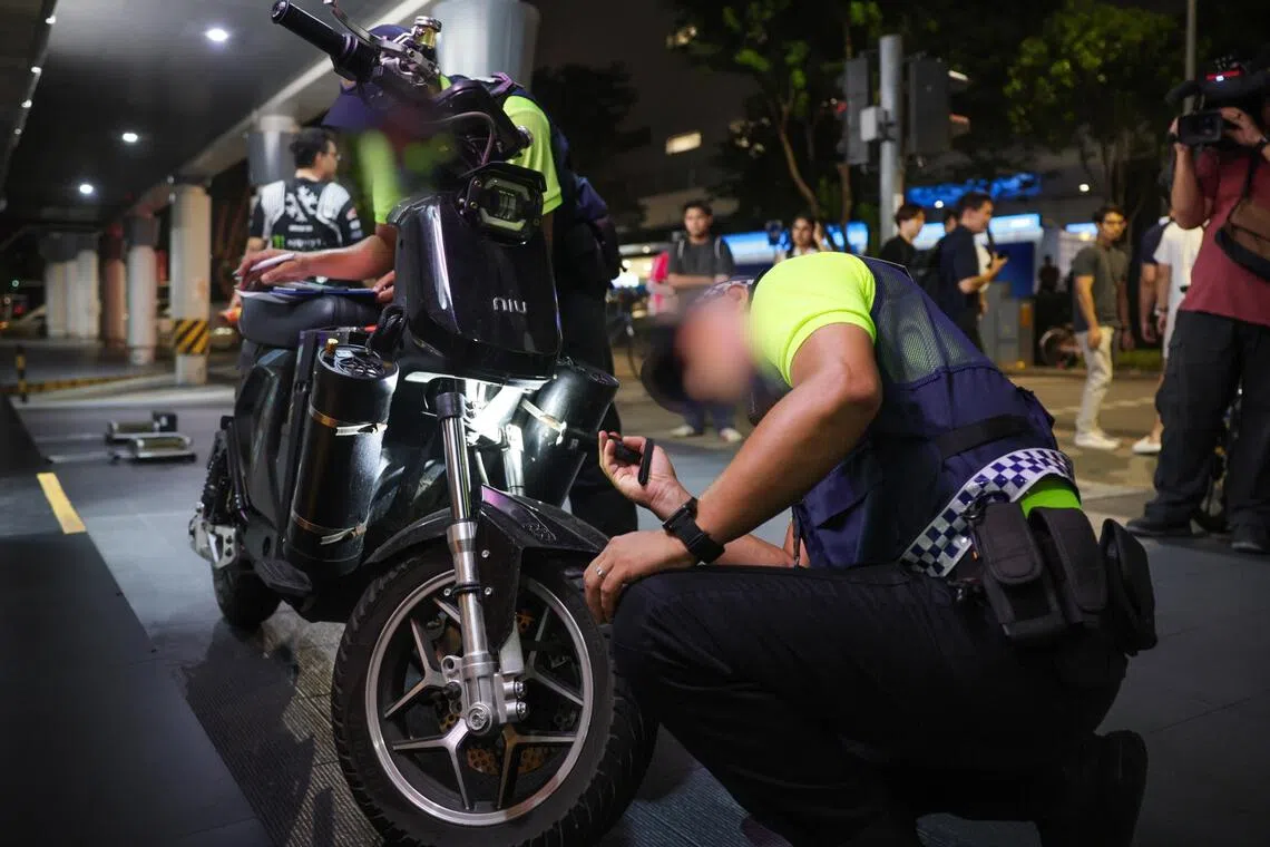 LTA enforcement officers inspecting a suspected non-compliant PMD during the enforcement check in Northpoint City in Yishun on Aug 3.
