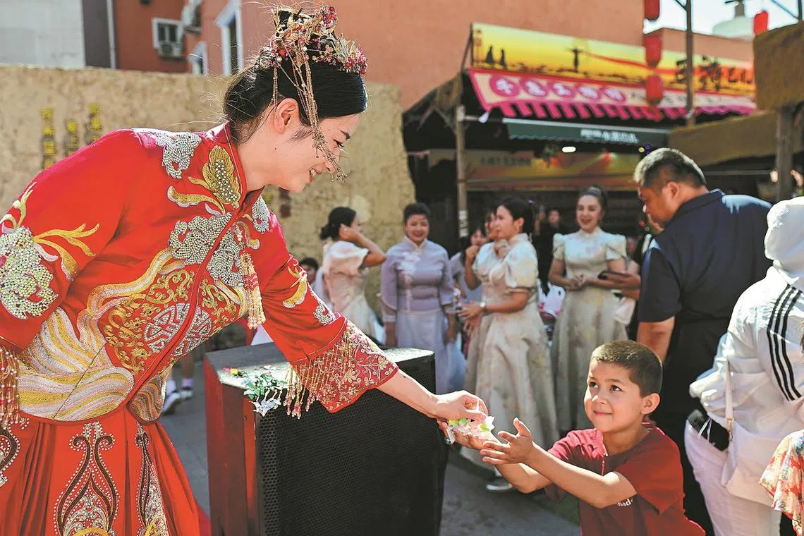 A bride gives sweets to a child at her wedding ceremony in Urumqi, Xinjiang Uygur autonomous region during Qixi Festival, or Chinese Valentine's Day. 